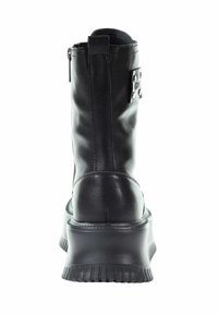 Czarne skórzane botki sięgające kostki z płaską, żłobioną podeszwą. Posiadają boczny zamek oraz metalowy tag z ćwiekami po zewnętrznej stronie. Gładka faktura.