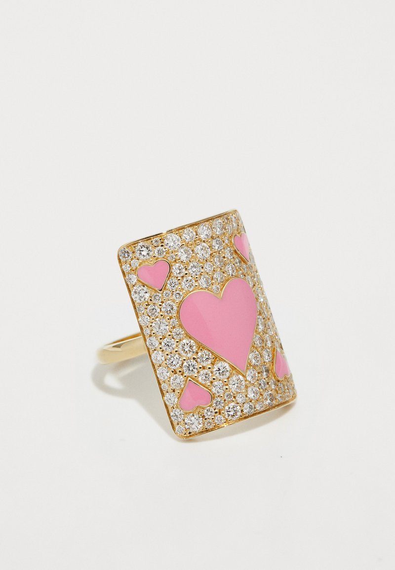 Anillo de oro con un diseño rectangular que presenta formas de corazones rosas y adornos de cristal transparente. Textura suave con acabado brillante.