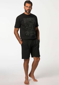 Camiseta de algodón negra con un estampado gráfico, combinada con pantalones cortos negros. Ambos prendas presentan un corte relajado y un diseño casual.