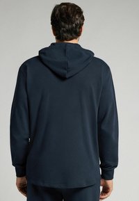 Sudadera azul marino fabricada con tejido suave, con capucha ajustable, mangas largas y un corte relajado. Textura suave con un diseño minimalista.