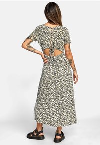 Maxi sukienka w kwiaty w kolorze czarnym z białymi i żółtymi wzorami. Krótkie rękawy, odkryty tył z wiązaniem oraz dopasowana talia. Teksturowana tkanina.