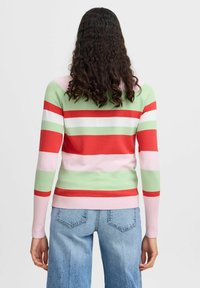 Pull rayé en vert, rouge, rose et blanc ; texture côtelée. Associé à un jean évasé bleu clair, vu de dos.