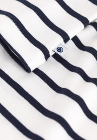 Maglione a righe blu navy e bianche, caratterizzato da una texture morbida con un'etichetta nell'angolo. Le righe sono distribuite in modo uniforme e orizzontale.