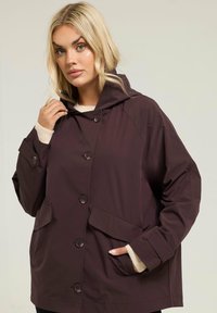 Veste à capuche bordeaux avec de gros boutons, poches latérales et coupe décontractée. Dotée d'une texture lisse et de poignets en tricot léger contrastant.