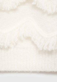 Bela pletena jopica z teksturiranim vzorcem in resastimi robovi na spodnjem delu, kar daje mehak in udoben videz.