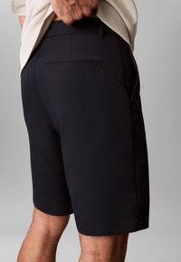 Pantaloni scurți bleumarin fabricați dintr-un material neted, având un buzunar în spate și detalii subtile cu logo-ul Calvin Klein. Croială ajustată cu linii curate.