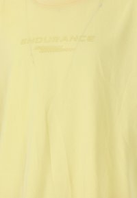 Ljusgul idrottströja med rund halsringning och en texturerad "ENDURANCE"-logotyp i kontrasterande tråd, med ett mjukt och lent tyg.