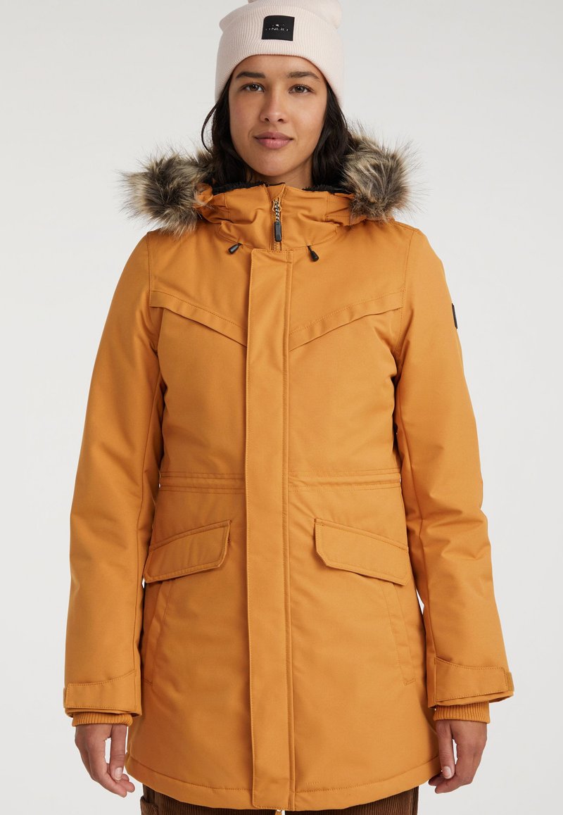 Chaqueta aislante naranja con cremallera frontal, capucha desmontable forrada de piel, bolsillos laterales y un diseño ajustado con una textura suave.
