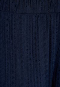 Abito blu navy in tessuto strutturato con righe verticali e piccoli tagli. Il materiale sembra leggero e traspirante.