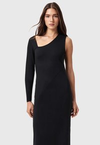 Musta, vartaloa myötäilevä mekko, jossa epäsymmetrinen yksikätinen malli ja pitkä hiha. Valmistettu sileästä, joustavasta materiaalista, jossa saumaominaisuudet.
