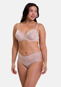 Set di reggiseno in pizzo e mutande a vita alta di un morbido colore nude, con motivi floreali e bordi ondulati. Spalline regolabili e senza ferretto.