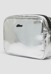 Metallisch silberne rechteckige Tasche mit glatter Textur, ausgestattet mit einem schwarzen Reißverschluss und einem geprägten Logo auf der Vorderseite.