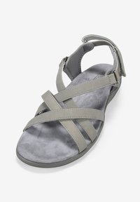 Sandalo grigio con cinturini incrociati, texture in suede morbido, cinturino alla caviglia regolabile e suola piatta. Progettato per comfort e supporto.