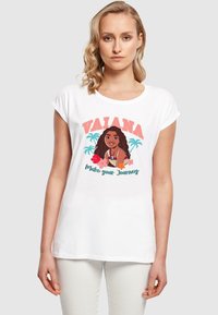Hvid t-shirt med et grafisk design af en karakter med mørkt hår, palmetræer og teksten "VAIAANA Make your Journey" i farverige skrifttyper.
