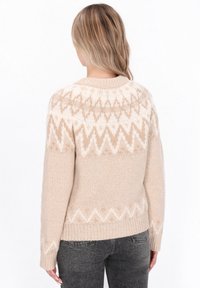 Pulover bej tricotat, cu un model geometric în crem, având guler rotund și mâneci lungi. Textură moale și croială relaxată.