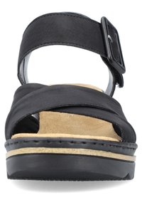 Zwarte leren sandaal met brede kruislings gespen, een gestructureerde zwarte gesp, een zachte beige suede voetbed en een lage zwarte rubberen zool.