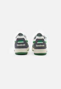 Reebok-sneakers med övre i vit och grå mocka, gröna accenter, strukturerad gummisula och framträdande logotyp på hälen.