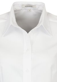 Camicia bianca a maniche lunghe con colletto classico, chiusura a bottoni e texture liscia. L'etichetta indica la taglia 36, design minimalista.
