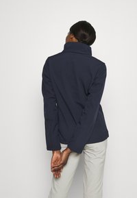 Granatowa kurtka z długim rękawem, o wysokim kołnierzu i dopasowanym kroju. Gładka faktura, widoczne szwy i prosty dół.