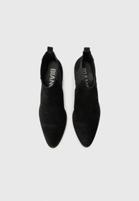 Black suede ankle boots with pointed toes and elastic side panels, displayed from above on a plain white background.