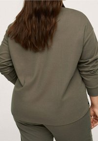 Suéter de manga larga color verde oliva con bajo redondeado, hecho de una tela suave. Presenta un corte holgado y puños acanalados.