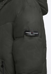 Groene pufferjas met een glanzende textuur, voorzien van een gladde oppervlakte, ritsluiting en een zwart stoffen label op de mouw.