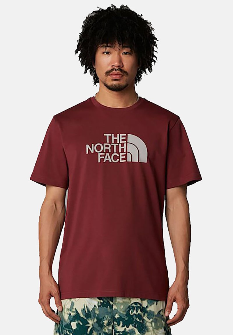 Camiseta de manga corta color burdeos, hecha de una tela suave, con un gran logo gris de "The North Face" en el pecho. Corte casual.