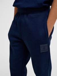 Navy blue sweatpants with elastic waistband and side pockets, featuring a raised Hummel bee logo patch on the thigh.