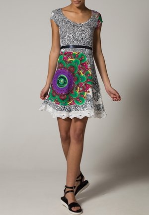 Kurzes, ärmelloses Kleid mit einem schwarz-weißen gemusterten Oberteil, einem bunten Blumenmuster in Grün, Lila und Rot sowie einem Saum mit Spitzenbesatz.