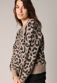 Luipaardprint trui in beige en zwart, met een zachte textuur, geribbelde manchetten en zoom, en een comfortabele pasvorm.