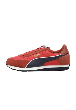 Zapatilla Puma roja y negra con suela blanca, parte superior de ante y tela, logo lateral y cordones, mostrada de lado externo sobre fondo blanco.