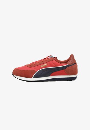 Zapatilla Puma roja y negra con suela blanca, parte superior de ante y tela, logo lateral y cordones, mostrada de lado externo sobre fondo blanco.
