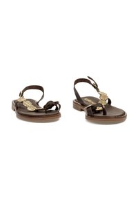 Sandalias de cuero marrón con suela plana, con una correa en el tobillo, diseño anudado y adornos florales en tono dorado en la parte delantera.