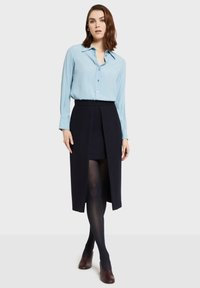 Světle modrá košile s dlouhým rukávem, límečkem a zapínáním na knoflíky, kombinovaná s tmavě modrou zavinovací sukní, černými punčochami a vínovými podpatky.