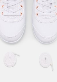 Hvite kanvas sneakers med metallisk rosegull øyler, flate hvite snørebånd, avrundet tå og teksturert stoff. To ekstra hvite snørebånd inkludert.
