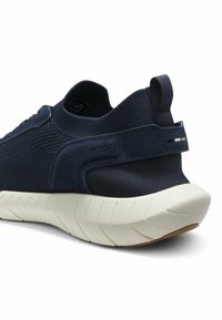 Sneaker in maglia blu navy con suola bianca spessa, cinturino in suede sul tallone e linguetta in tessuto sul retro.