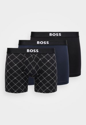 Tre par BOSS boxershorts: ett ensfarget svarte, ett ensfarget marineblå, ett mønstret med hvitt diamantmønster på svart bakgrunn.