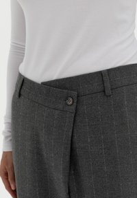 Grijze gestreepte broek van zachte stof, met een knoopsluiting, zijzakken en een tailoring pasvorm bij de taille.