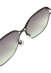 Mustadel käeservega prillid suurtel, nurgeliste läätsedel, millel on hallist helesinise gradient. Selged nina padjad on kaasas.