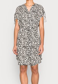 Abito floreale in nero e crema, con scollatura a V, maniche corte e vita regolabile con cordino. Tessuto morbido e leggero con una vestibilità ampia.