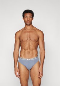 Graue Baumwollslips mit einem kontrastierenden weißen und grauen Bund, featuring einem Logostickerei auf der Vorderseite und einem figurbetonten Design.