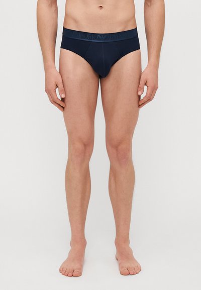Námorníckomodré bavlnené slipy s jemným elastickým pásom, na ktorom je logo Emporio Armani. Navrhnuté s nízkym strihom a hladkou textúrou.