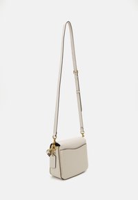 Borsa a tracolla in pelle di un beige chiaro, forma rettangolare, con un flap arrotondato, tracolla regolabile e dettagli in metallo dorato.