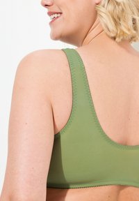 Olivgrüner Bralette mit breiten Trägern, glattem Stoff und kontrastierenden Nähten an den Kanten. Schlichtes, minimalistisches Design.