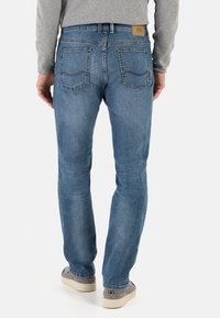 Jeans en denim bleu clair avec une coupe droite, cinq poches, et une taille mi-haute. L'arrière comporte deux poches cousues et une étiquette de marque.