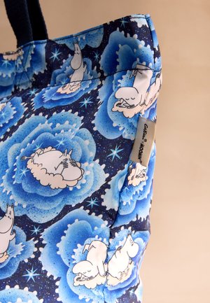 Zils tote maisiņš ar melnām rokturiem, dekorēts ar baltām zīmēto multfilmas varoņu figūrām uz pūkainām debesu mākoņiem, zvaigžņotas debess fonā.