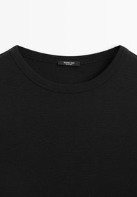 Sort bomulds T-shirt med rund halsudskæring, ribbet tekstur og et mærke indeni med teksten "Massimo Dutti, Made in India."