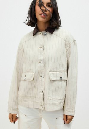 Beige gestreifte Jacke mit einem dunkelbrown Kordkragen, ausgestattet mit großen Fronttaschen und einer Knopfleiste. Glatte Textur, lockere Passform.