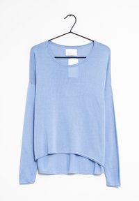 Jasnoniebieska koszula z długim rękawem zawieszona na czarnym haczyku. Posiada okrągły dekolt i zaokrąglony dół oraz teksturowaną tkaninę.