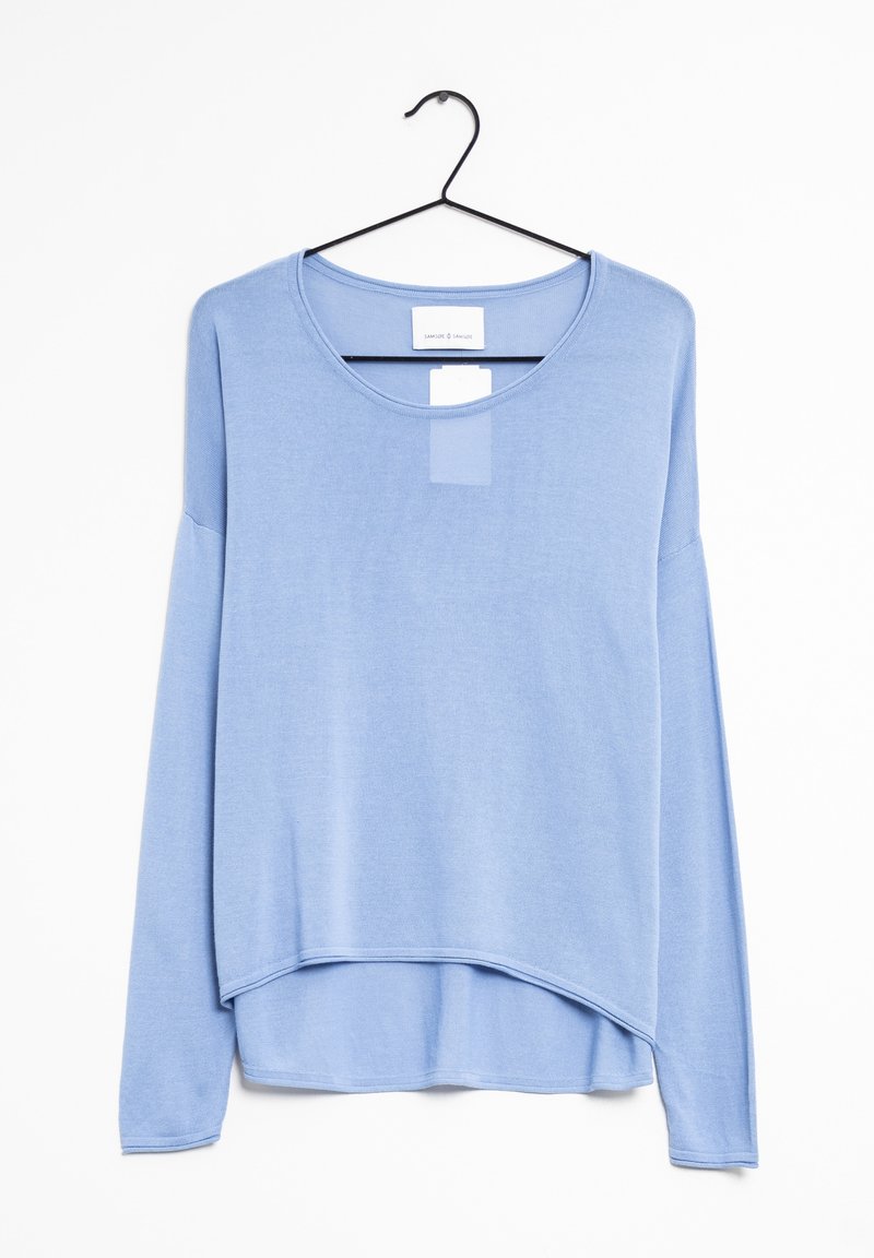 Jasnoniebieska koszula z długim rękawem zawieszona na czarnym haczyku. Posiada okrągły dekolt i zaokrąglony dół oraz teksturowaną tkaninę.